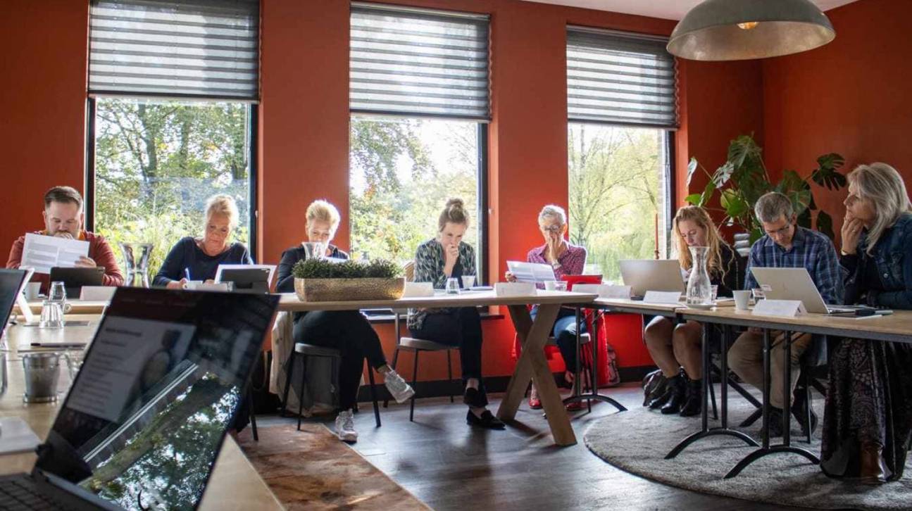 Schrijfsessie, mensen aan lange tafel aan het schrijven